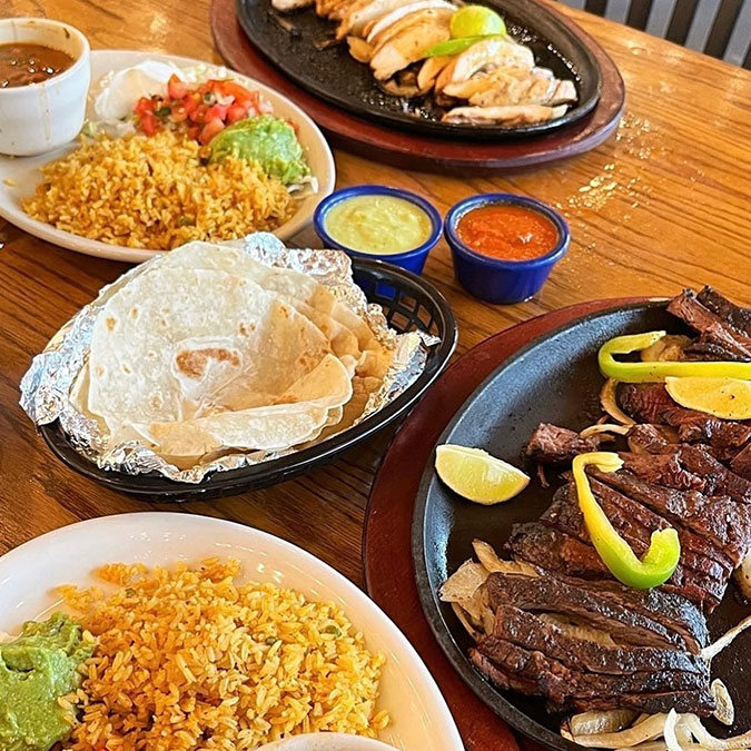 Texas-style plates of grilled meat with rice, beans, guacamole, and sauces at Maria Mia Cantina.