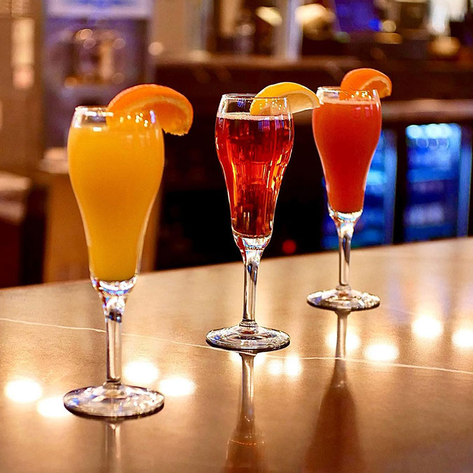 Three colorful cocktails at Maria Mia Tex-Mex Cantina in Texas, each with citrus garnishes.