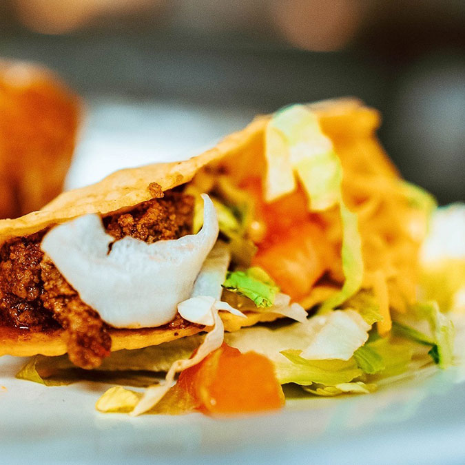 A crispy Texas taco with beef, lettuce, tomato, and cheese at Maria Mia Tex-Mex Cantina.