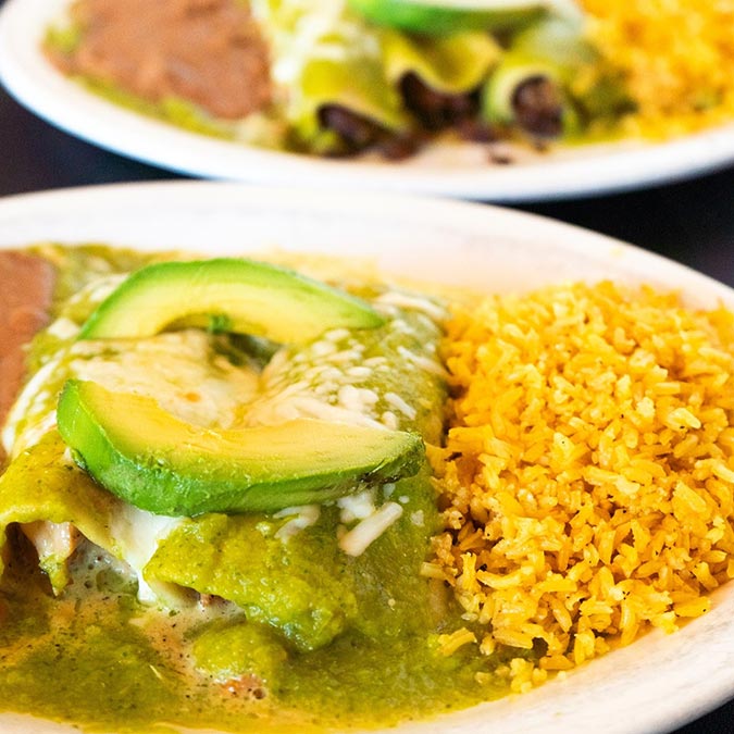 Plate of enchiladas with green sauce, avocado, beans, and rice at Maria Mia Tex-Mex Cantina.