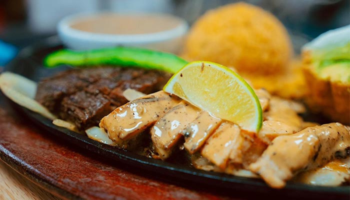 Sliced grilled chicken with sauce, rice, steak, and avocado at Maria Mia Tex-Mex Cantina College Station.