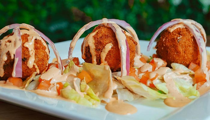 Three breaded balls on lettuce with veggies, sauce, and onion at Maria Mia Tex-Mex Cantina.