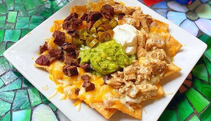 Plate of nachos with melted cheese, steak, chicken, and more at Maria Mia Tex-Mex Cantina Texas.